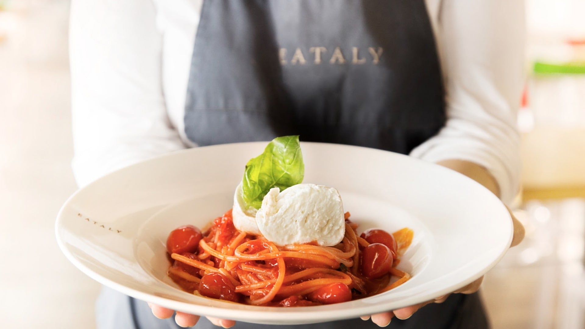 Serveuse portant un plat de spaghetti mozzarella 